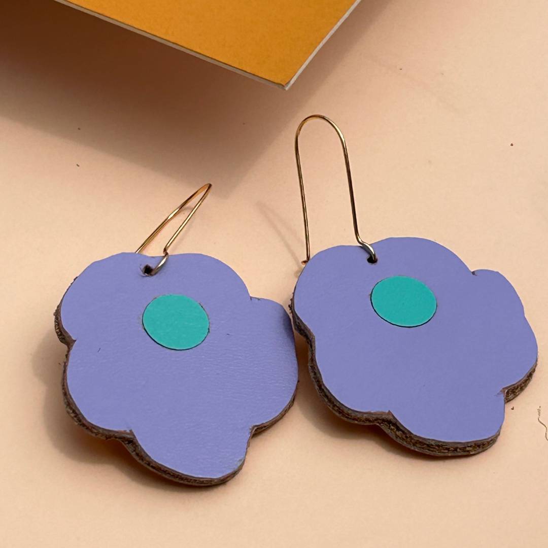 Aretes de cuero recuperado reversibles en forma de margarita. Diseño costarricense. Joyería artesanal contemporánea sostenible. Joyería de autor. 