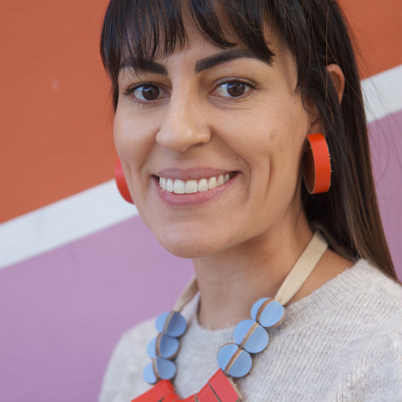Mujer usando aretes de madera con cuero naranja