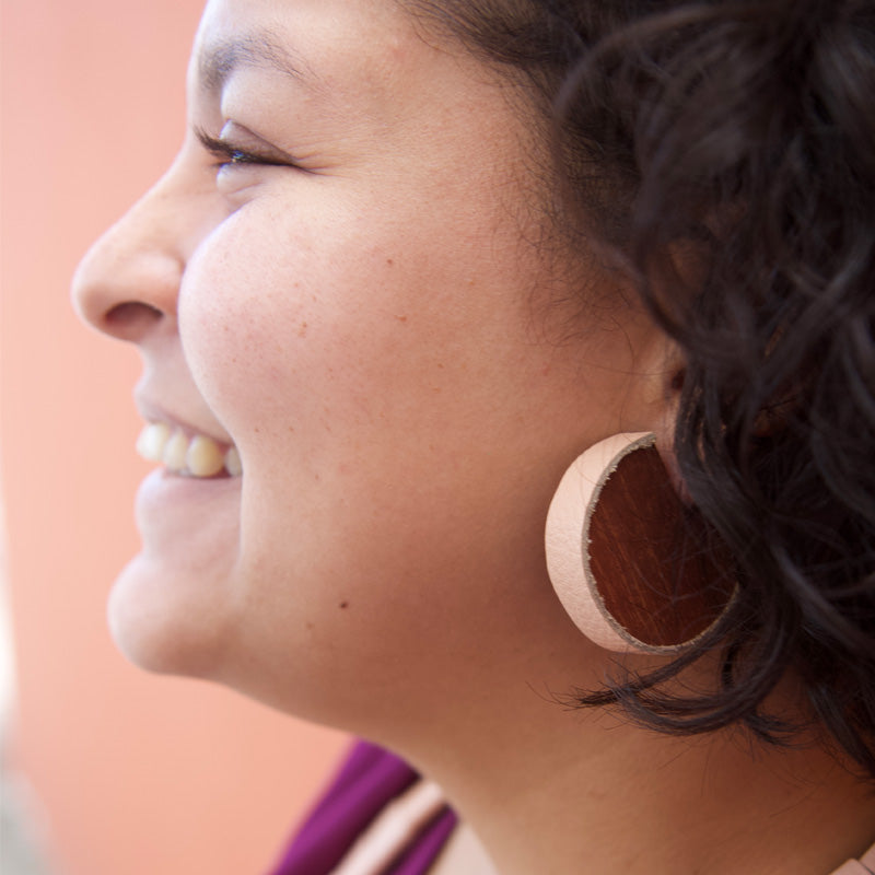 Detalle de aretes de madera con cuero salmón
