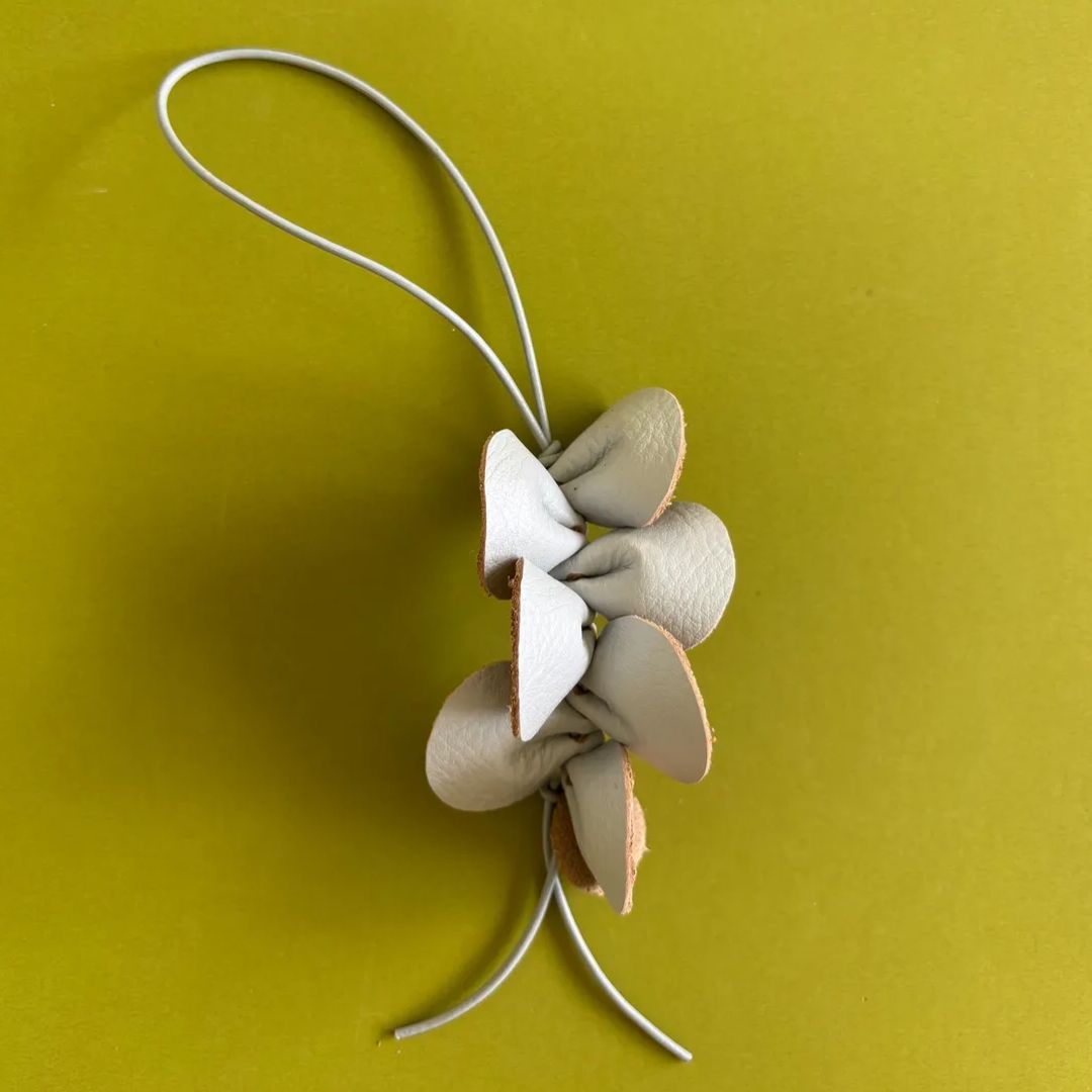 Detalle artesanal de la orquídea Guaria de cuero metalizado de 8x5 cm