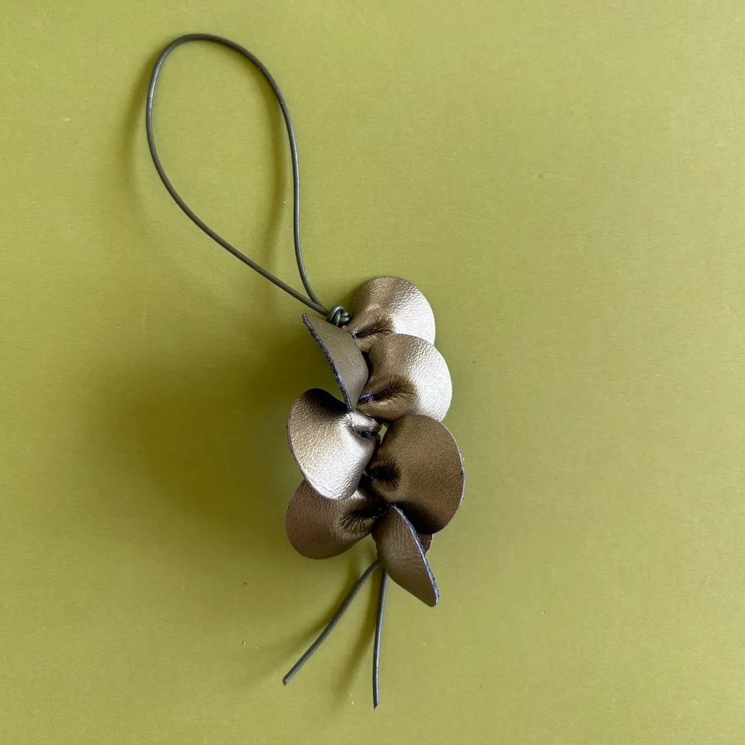 Detalle artesanal de la orquídea Guaria de cuero metalizado de 8x5 cm