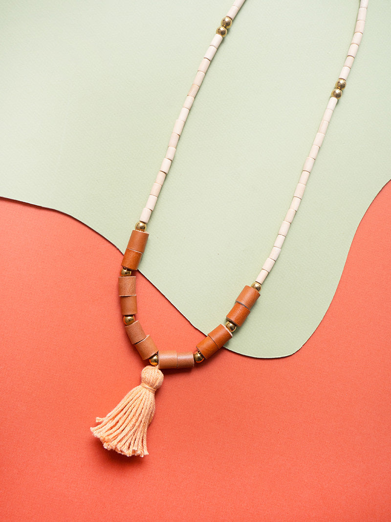 Collar largo de piezas de madera natural con rollitos en cuero color miel, bolitas doradas de acero inoxidable y rollito de hilos de algodón en naranja teñidos con tintes naturales de semillas de achiote