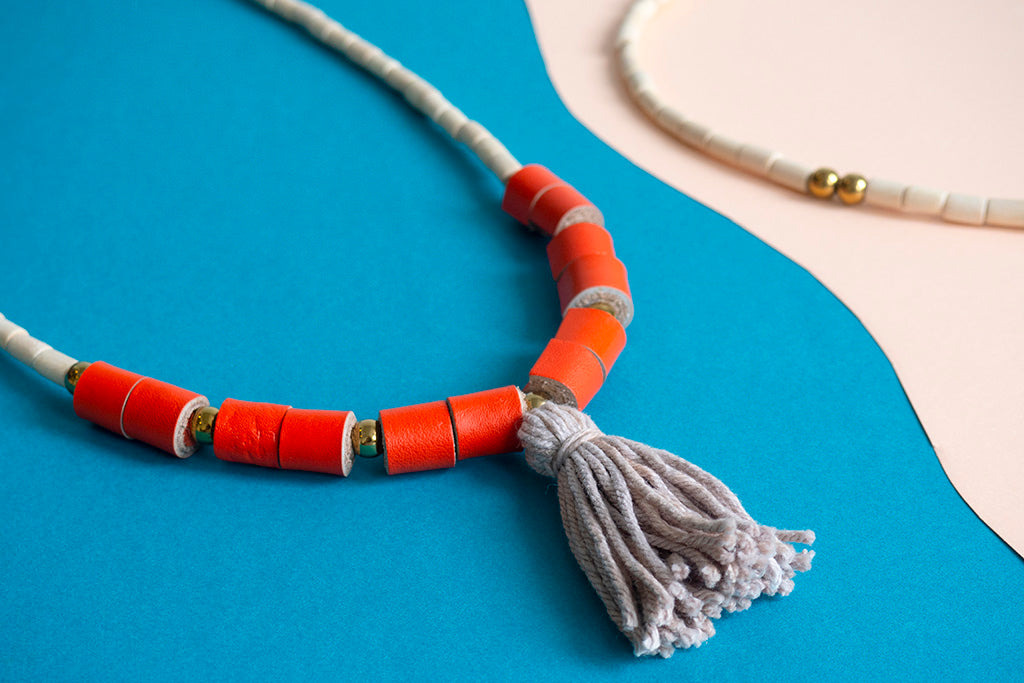 Detalle de collar BOHO en rollitos naranja y rollito de hilos de algodón gris