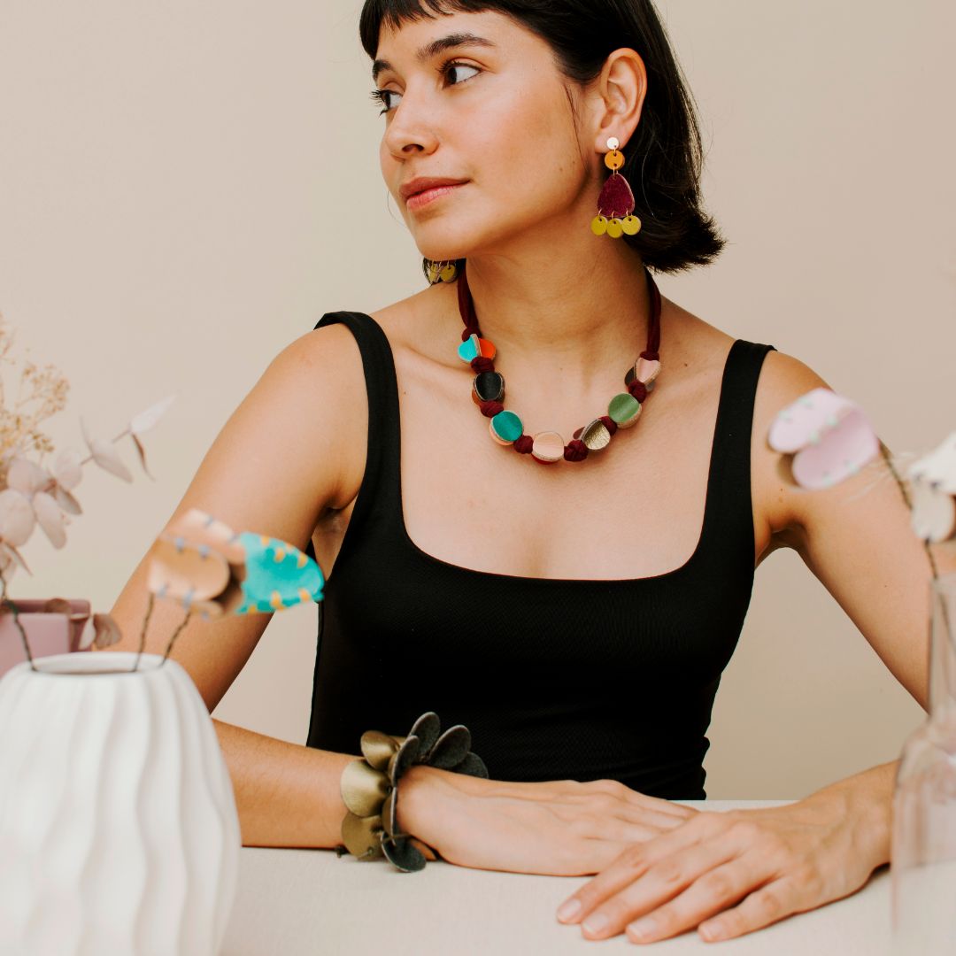 Mujer usando el collar caleidoscopio en diferentes colores combinados. Collar de cuero recuperado. Diseño costarricense. 