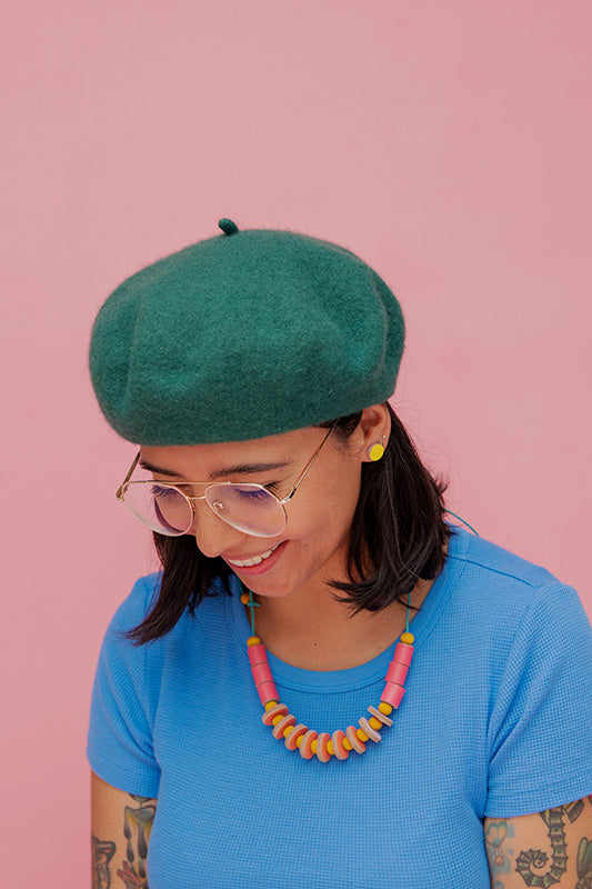 Mujer con blusa azul usando el collar Maca de cuero en color fucsia y amarillo