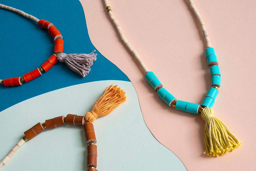 Detalle de las tres versiones de color de los collares BOHO sobre fondo de color salmón, celeste y azul