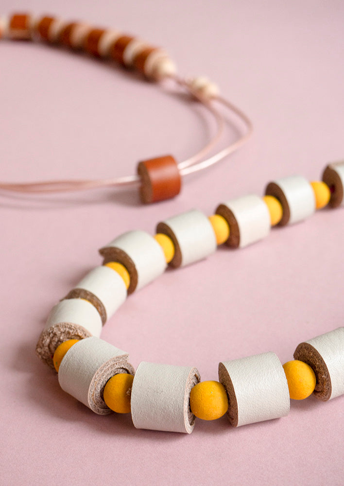 Detalle rollitos vainilla con bolitas de madera amarilla sobre fondo rosado claro