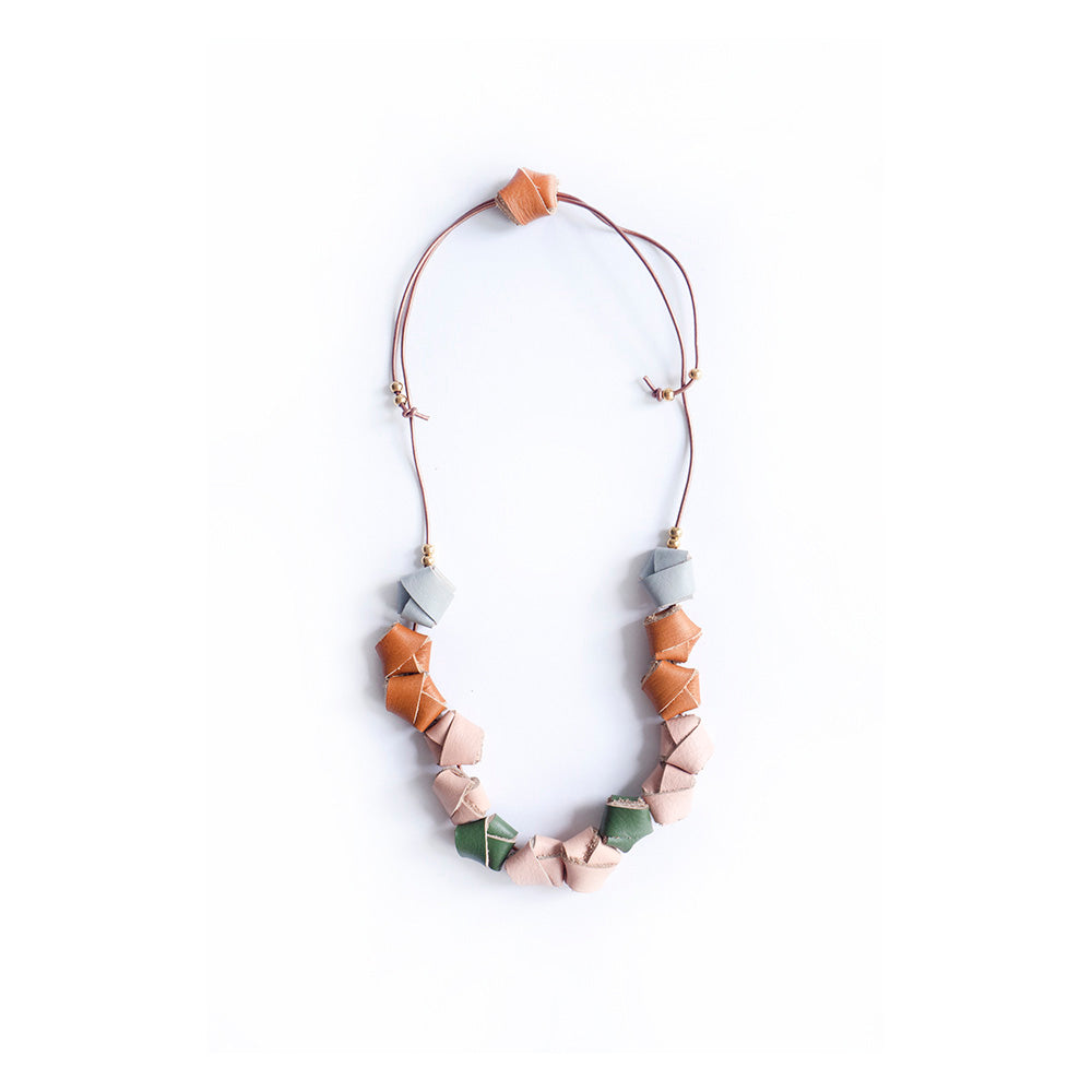 Collar completo hecho con nudos en cuero de colores gris, miel, salmón y verde olivo, cierre ajustable para usarlo corto o largo con cordón de cuero café y bolitas doradas de acero inoxidable