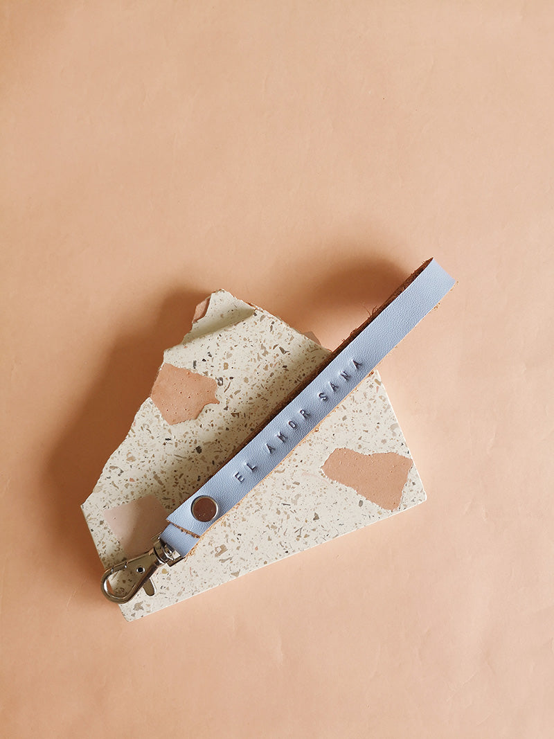 Llavero de cuero en color celeste con la frase El amor sana estampada a mano