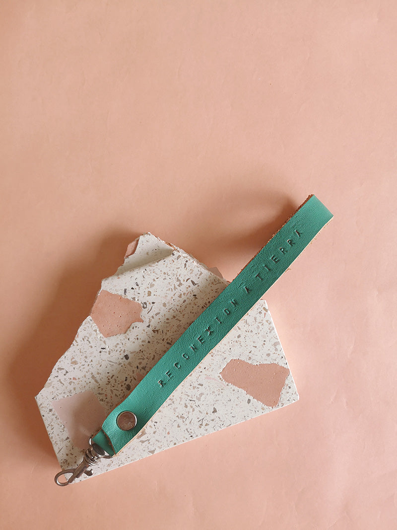 Llavero de cuero en color turquesa con la frase Reconexión a tierra estampada a mano